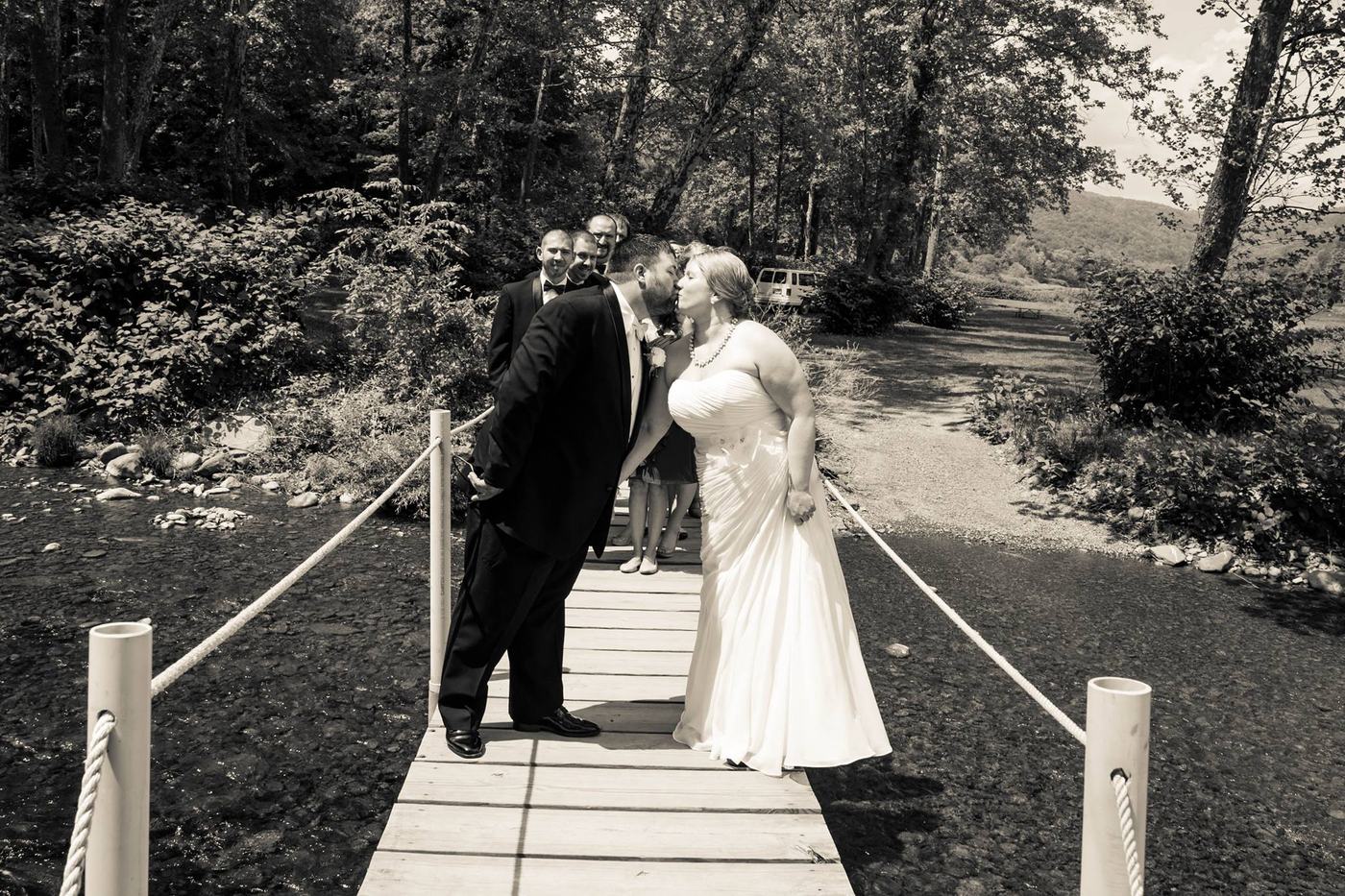 Black and white photo of newlyweds kissing on the bridge